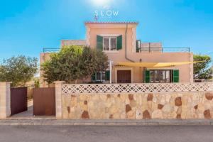 a house behind a stone wall with a fence at Villa Sa Llimonera by Slow Villas in Cala Llombards +34 photos