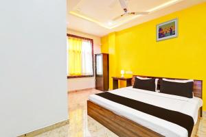 a bedroom with a large bed with a yellow wall at Super Hotel O Stayo in Patancheru