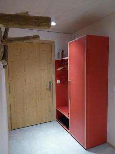 a red refrigerator in a room with a wooden door at Biala Biobergün in Bergün