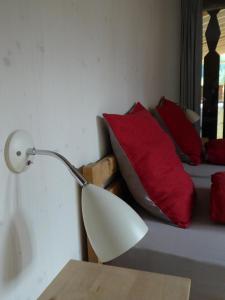 a lamp sitting next to a bed with red pillows at Biala Biobergün in Bergün +9 photos