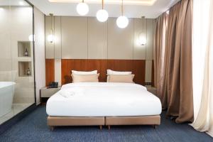 a bedroom with a large white bed and a bath tub at TheMirell Hôtel Dakhla in Oulad Akkou