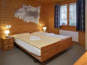a bedroom with a large bed in a wooden wall at Apartment Chäs Gruebi Apt-S by Interhome in Wengen