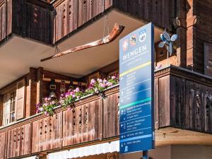 a sign in front of a building with flowers on a balcony at Apartment Chäs Gruebi Apt-S by Interhome in Wengen