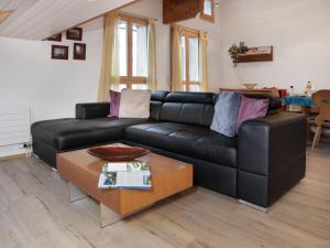 a black leather couch in a living room with a table at Apartment Breithorn Residence Apt-09 by Interhome in Wengen