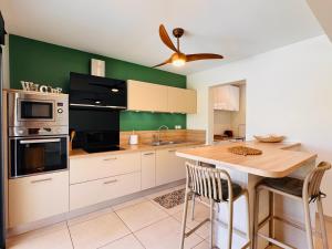 a kitchen with white cabinets and a ceiling fan at Villa Parenthèse - Piscine & Bungalow - 8 Pers in Trois Bassins