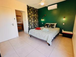 a bedroom with a bed and a green wall at Villa Parenthèse - Piscine & Bungalow - 8 Pers in Trois Bassins