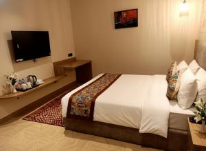 a hotel room with a bed and a flat screen tv at Klyra Hotel in Hyderabad +6 photos