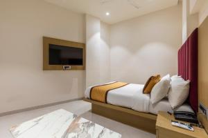 a bedroom with a bed and a tv on a wall at Hotel Mint in Thane +25 photos