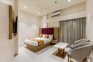 a hotel room with a bed and a chair at Hotel Mint in Thane
