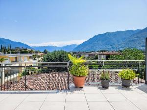 a balcony with potted plants and mountains in the background at Apartment Residenza Corallo Apt-201 B by Interhome in Ascona +13 photos