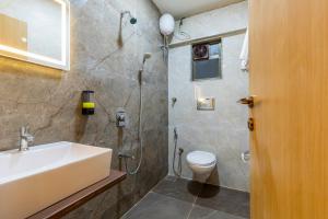a bathroom with a shower and a sink and a toilet at Hotel Mint in Thane