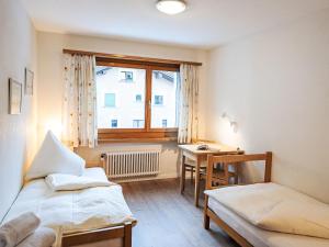 a room with two beds and a desk and a window at Apartment Chesa Islas by Interhome in Pontresina