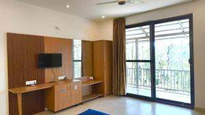 a living room with a tv and a large window at GM Farm Mountain View Homestay in Avathi