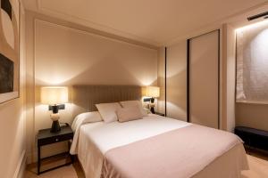 a bedroom with a white bed and two lamps at Suite Plaza Nueva in Seville