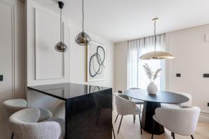 a dining room with a black table and chairs at Suite Plaza Nueva in Seville