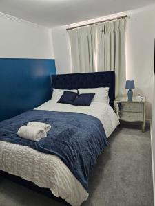 ein Schlafzimmer mit einem blauen Bett mit einem Handtuch darauf in der Unterkunft Stylish 5-Bed Solihull Stay Near NEC & Airport in Solihull