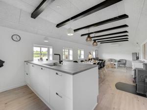 a kitchen with white cabinets and a living room at Holiday Home Giesela - 975m from the sea by Interhome in Ringkøbing