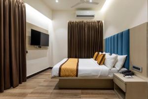 a hotel room with a bed and a tv at Hotel Mint in Thane