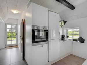 a kitchen with white cabinets and a stove at Holiday Home Giesela - 975m from the sea by Interhome in Ringkøbing +16 photos