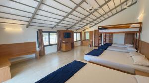 a large room with two beds and a television at GM Farm Mountain View Homestay in Avathi +59 photos