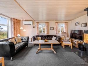 Una sala de estar con un sofá, una mesa y un televisor. en Holiday Home Brawith - 700m to the fjord by Interhome, en Ringkøbing