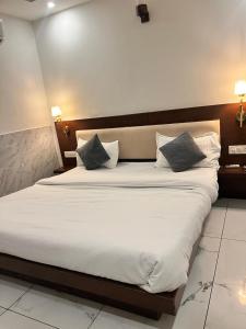 ein Schlafzimmer mit einem großen Bett mit weißen Laken und Kissen in der Unterkunft Hotel Park land in Zirakpur