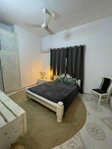 a bedroom with a large bed and a chair at B4 Apartment Stone Town in Zanzibar City