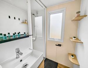 a white bathroom with a sink and a window at Green harmony in Litteau +12 photos