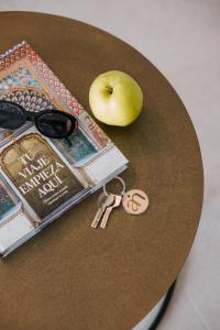 ein Tisch mit einem Buch, einer Brille und einem Apfel in der Unterkunft Blue Balcony Suites by Airnest in Melenara