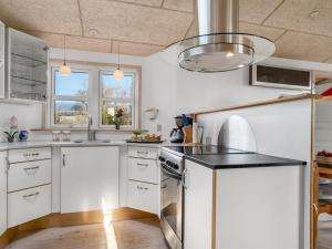 a kitchen with white cabinets and a black counter top at Holiday Home Skarthi - 200m from the sea by Interhome in Sæby