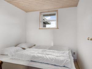 a bed in a white room with a window at Holiday Home Skarthi - 200m from the sea by Interhome in Sæby