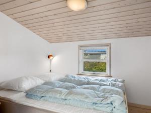 a bed in a white room with a window at Holiday Home Skarthi - 200m from the sea by Interhome in Sæby