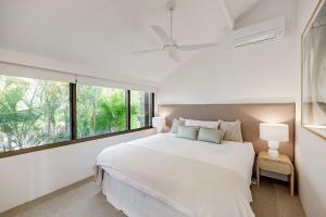 une chambre blanche avec un grand lit et une fenêtre dans l'établissement Bella Vista Noosa Luxury on White Sands, à Noosaville