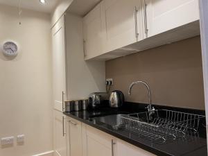 a kitchen with white cabinets and a sink at Moat House 6 in Fort Augustus