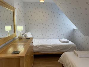 een slaapkamer met 2 bedden en een bureau met een spiegel bij Moat House 6 in Fort Augustus