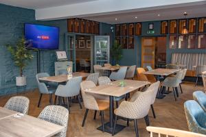 a restaurant with tables and chairs and a tv on the wall at Bells Hotel in Coleford