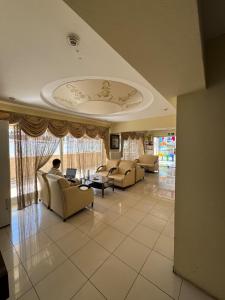 a living room with couches and a person sitting on a laptop at Alya otel in Burdur