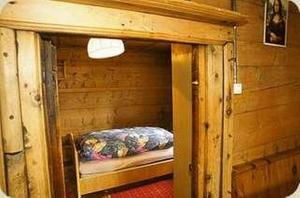 a small room with a bed in a log cabin at Cad Maté 2 in Maloja