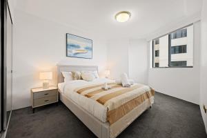 ein weißes Schlafzimmer mit einem großen Bett und einem Fenster in der Unterkunft The Relaxation CBD w Parking Desk Gym Pool in Sydney
