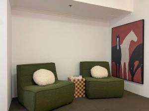 zwei grüne Stühle stehen in einem Raum mit einem Gemälde in der Unterkunft The Relaxation CBD w Parking Desk Gym Pool in Sydney
