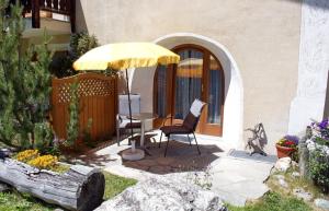 un patio con una mesa y una sombrilla amarilla en Chardun, en Celerina 13 fotos más