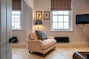 a living room with a chair and two windows at Stunning High Street Hideaway in Cheltenham in Cheltenham