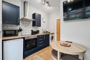 a kitchen with a table and a small kitchen with blue cabinets at Kendal Lane Apartments in Central Station
