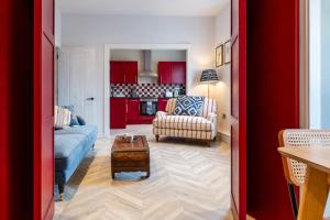 a living room with red cabinets and a blue couch at Stunning High Street Hideaway in Cheltenham in Cheltenham