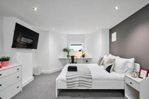 a white bedroom with a white bed and a tv at Kendal Lane Apartments in Central Station