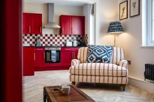 a living room with red cabinets and a chair at Stunning High Street Hideaway in Cheltenham in Cheltenham