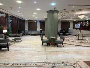 a lobby with a waiting area with chairs and tables at Sky View Hotel, Madinah in Medina