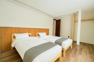 two beds in a hotel room with wooden floors at The Lobs 5, Rusutsu in Kimobetsu