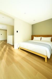 a bedroom with a large white bed and wooden floors at The Lobs 5, Rusutsu in Kimobetsu +1 photo
