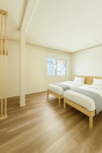 two beds in a white room with wooden floors at The Lobs 5, Rusutsu in Kimobetsu